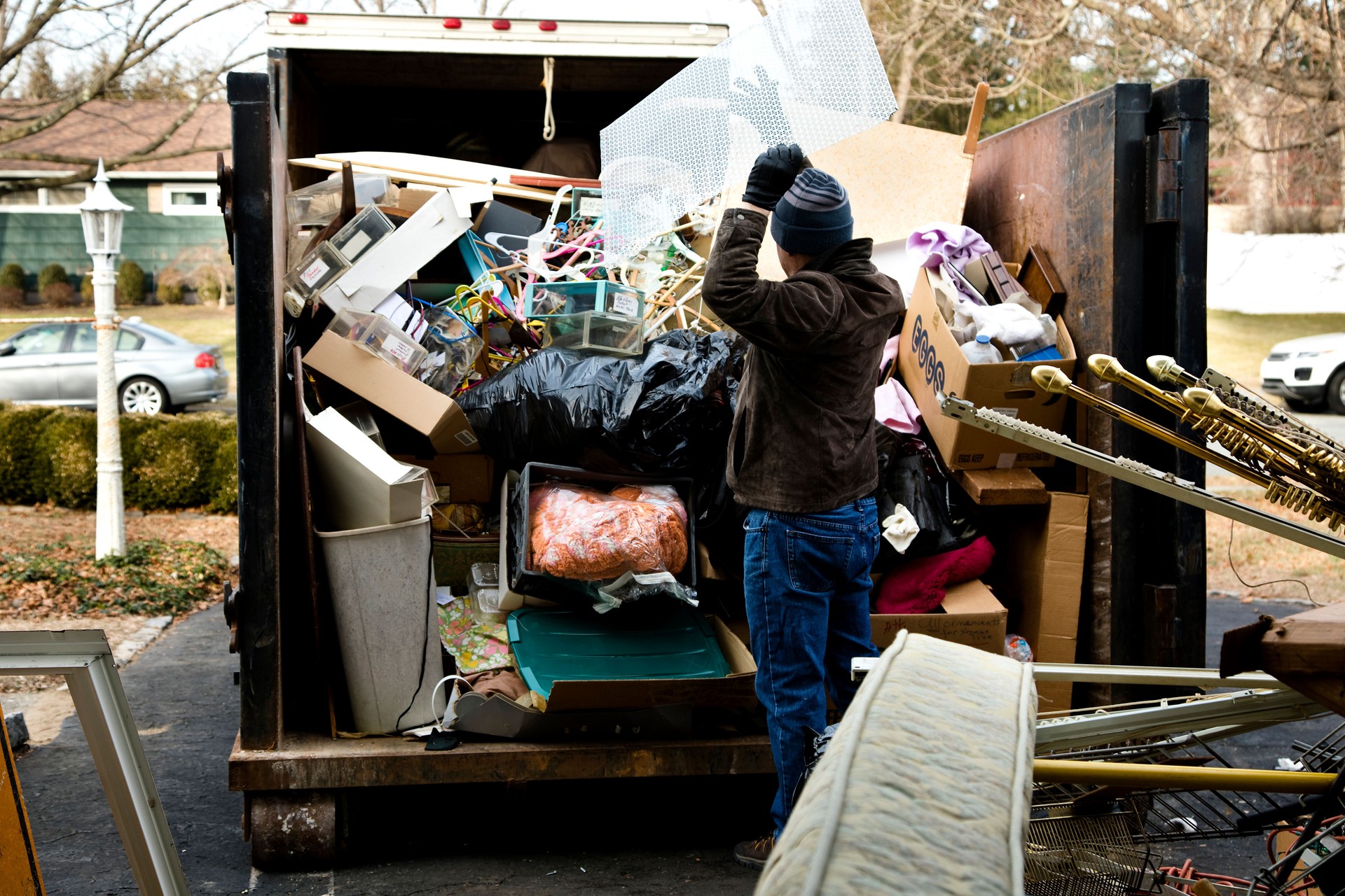 Workman loading dumpster in driveway